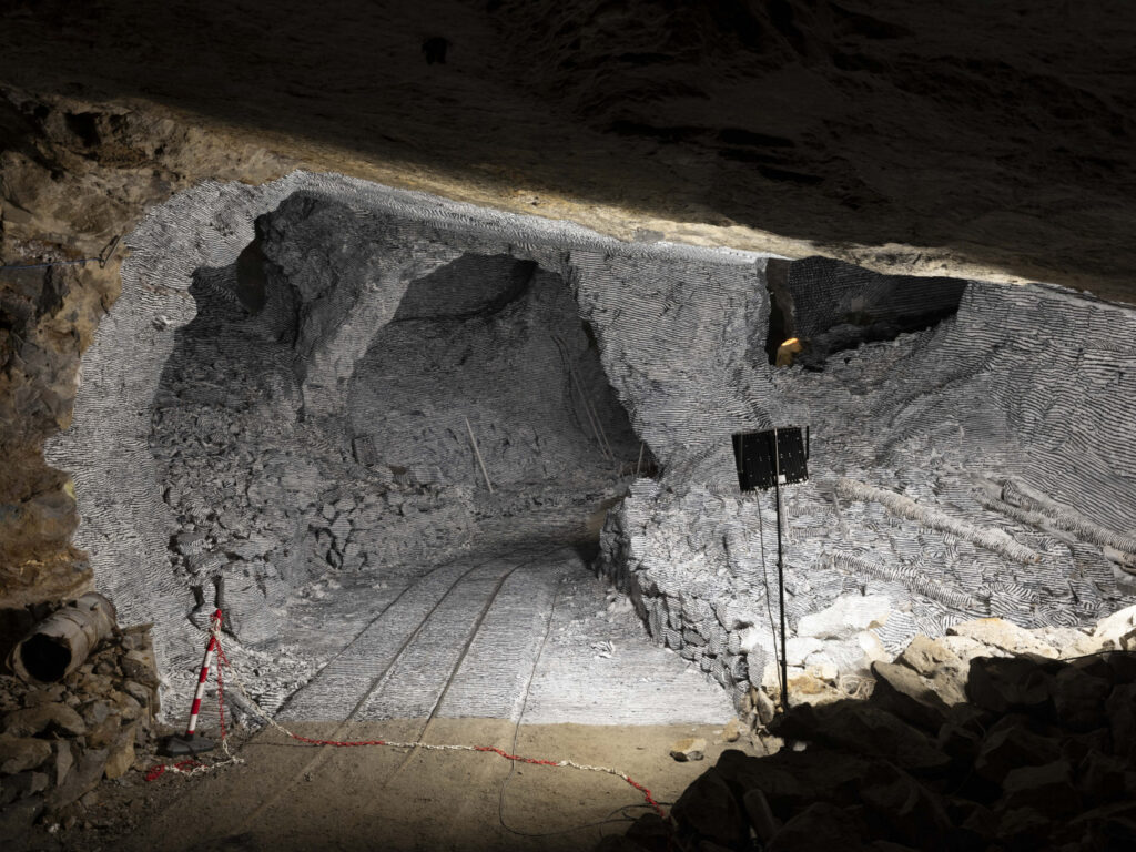 A colour photo of an illuminated network of mine tunnels with a flash lamp in the foreground